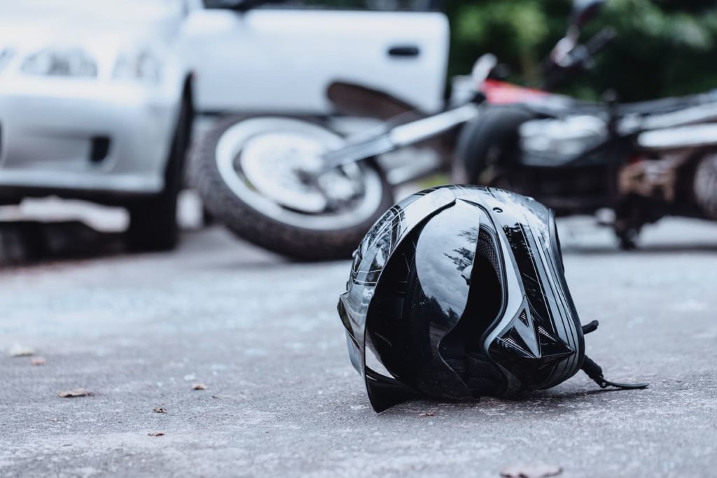 photo of helmet on street next to motorcycle after accident